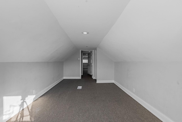 bonus room featuring vaulted ceiling, dark carpet, and baseboards