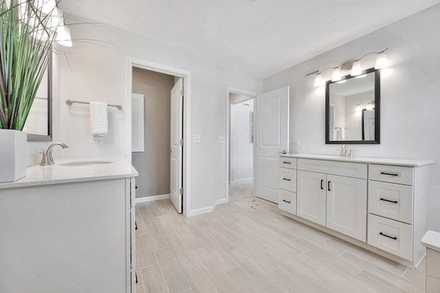 bathroom with wood finish floors, two vanities, and a sink