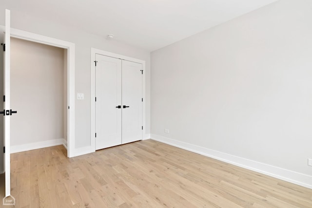 unfurnished bedroom featuring a closet, light wood-style flooring, and baseboards