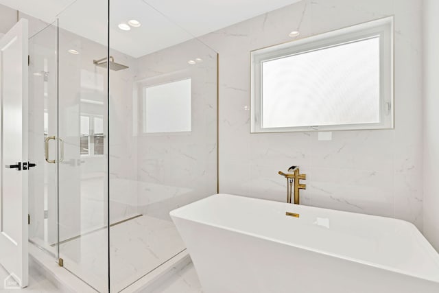 bathroom with marble finish floor, plenty of natural light, a marble finish shower, and a soaking tub