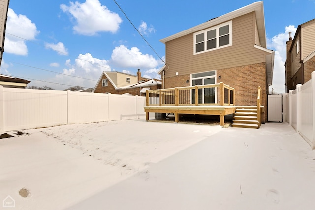 rear view of property featuring brick siding, a fenced backyard, and a wooden deck