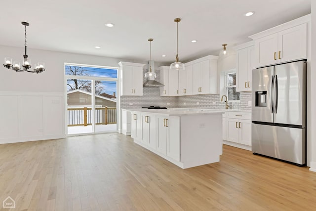 kitchen featuring light countertops, stainless steel fridge, hanging light fixtures, and white cabinetry