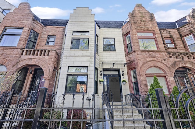 townhome / multi-family property featuring a fenced front yard and roof with shingles