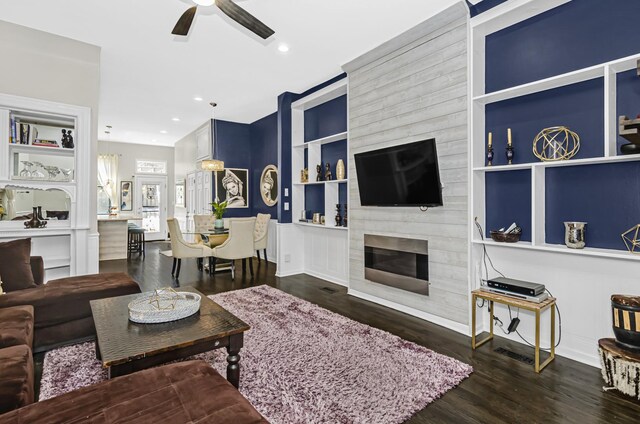 living room with dark wood finished floors, a ceiling fan, built in shelves, a fireplace, and recessed lighting