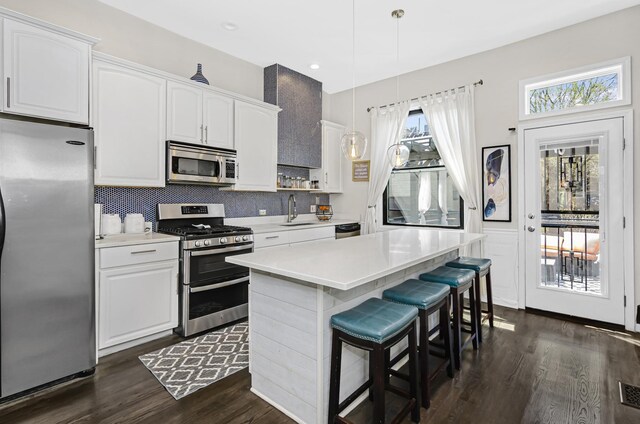 kitchen featuring light countertops, appliances with stainless steel finishes, white cabinetry, and pendant lighting