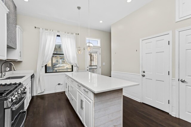 kitchen with decorative light fixtures, light countertops, white cabinets, a kitchen island, and a sink