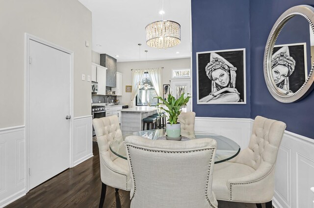 dining room with recessed lighting, a decorative wall, a notable chandelier, wainscoting, and dark wood finished floors