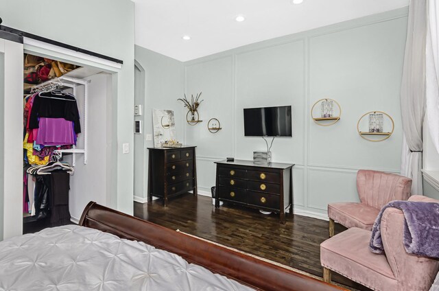 bedroom featuring dark wood finished floors, a closet, a decorative wall, and recessed lighting