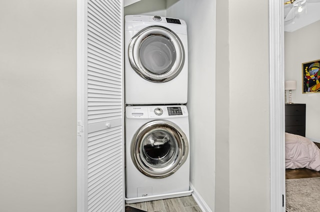 washroom with laundry area, baseboards, wood finished floors, and stacked washer and clothes dryer