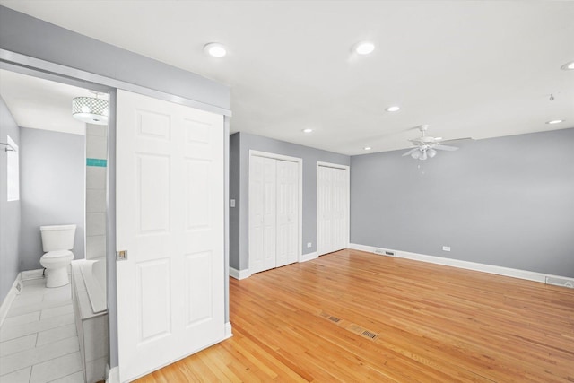 interior space featuring visible vents, baseboards, light wood-type flooring, two closets, and recessed lighting