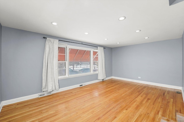 unfurnished room featuring light wood-style flooring, visible vents, and baseboards