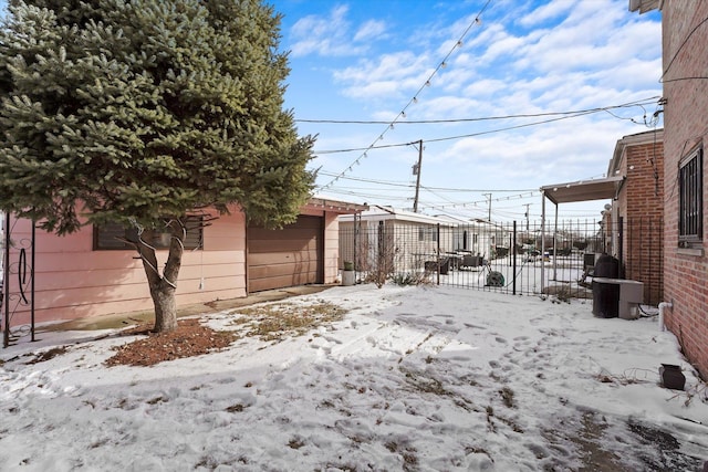 yard covered in snow featuring a garage and fence