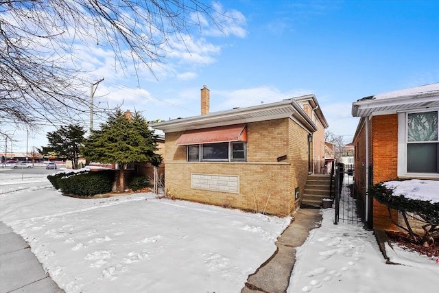 view of front of home featuring brick siding and a chimney