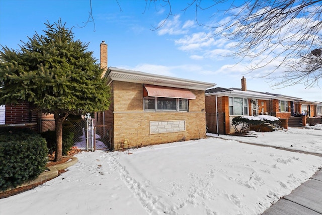 view of front facade with brick siding, a chimney, and fence