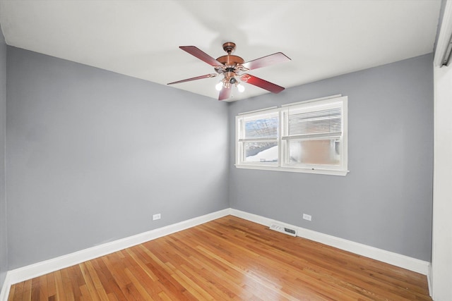 spare room with baseboards, visible vents, ceiling fan, and wood finished floors