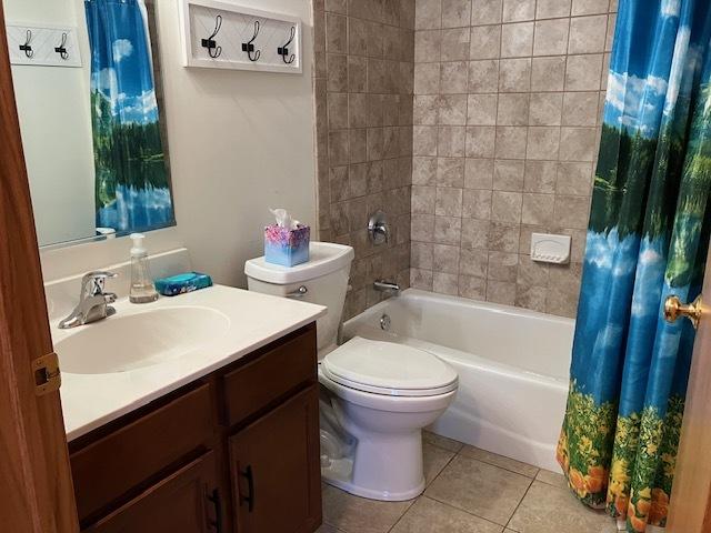 full bathroom featuring vanity, shower / bath combo, tile patterned flooring, and toilet