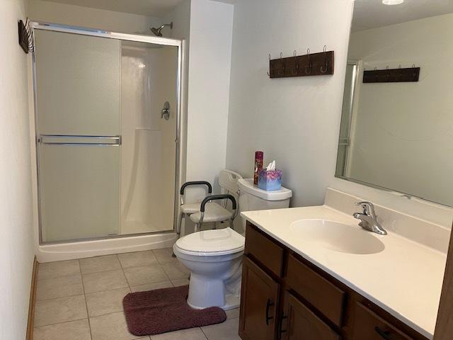 bathroom with toilet, a shower stall, vanity, and tile patterned floors