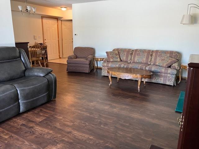 living room with dark wood-type flooring and a notable chandelier