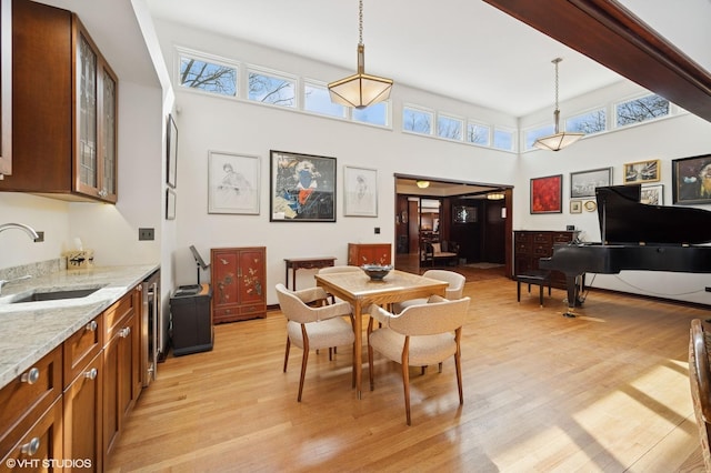 dining area with a high ceiling, plenty of natural light, and light wood finished floors