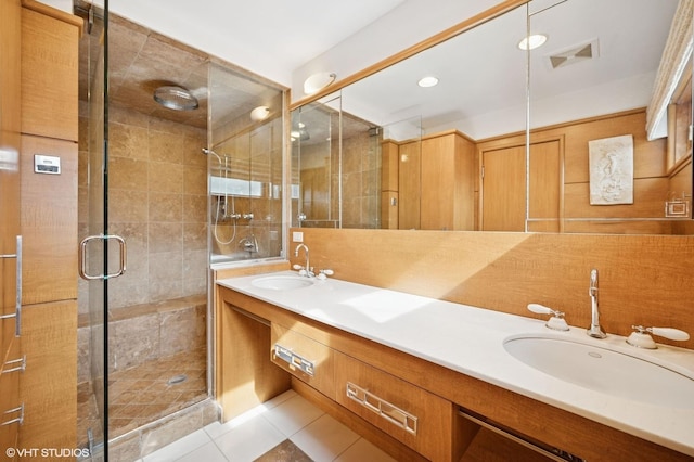 bathroom featuring double vanity, a stall shower, visible vents, tile patterned floors, and a sink