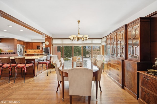 dining area with light wood finished floors, recessed lighting, and a notable chandelier