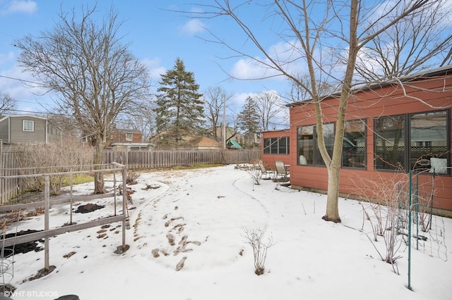 yard covered in snow featuring fence and a sunroom