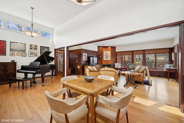 dining space with light wood finished floors, a high ceiling, and visible vents