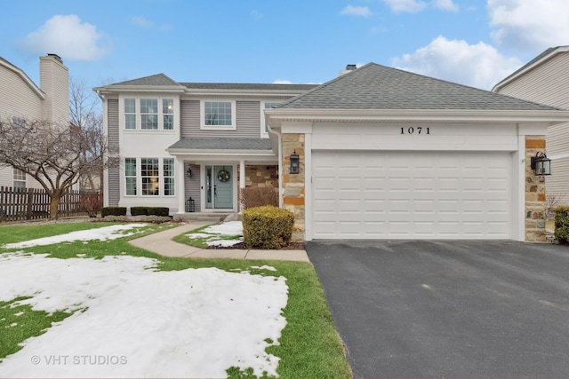 view of front of property with a garage, stone siding, aphalt driveway, and fence