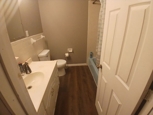 bathroom featuring toilet, vanity, wood finished floors,  shower combination, and baseboards