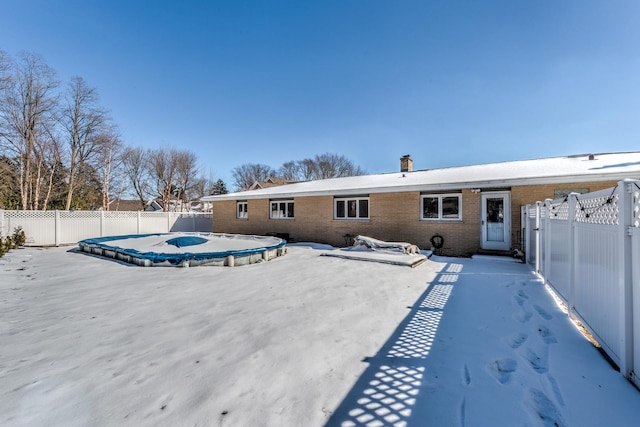 rear view of house with a fenced in pool, brick siding, and a fenced backyard