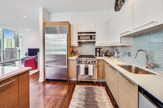 kitchen featuring high end appliances, light countertops, a sink, and white cabinetry