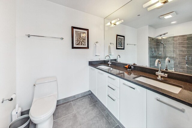 bathroom with toilet, double vanity, a sink, and tile patterned floors