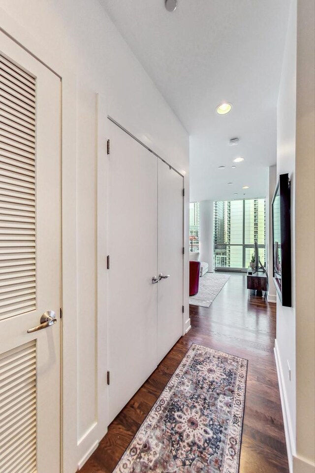 hallway featuring floor to ceiling windows, baseboards, dark wood-type flooring, and recessed lighting