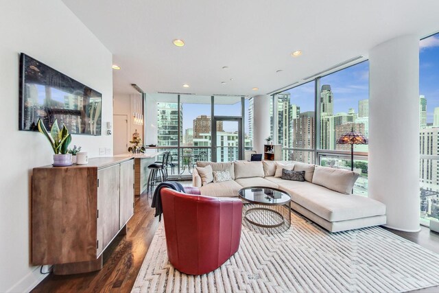 living room with a view of city, dark wood-type flooring, a wall of windows, and recessed lighting