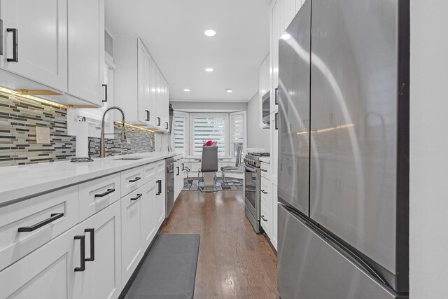 kitchen featuring appliances with stainless steel finishes, dark wood-style flooring, white cabinetry, and a sink