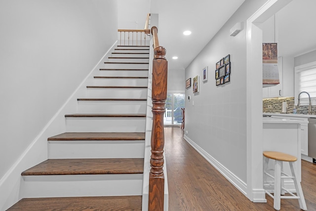 staircase featuring recessed lighting, wood finished floors, and baseboards