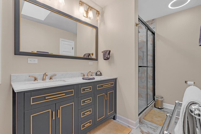 bathroom with a skylight, a sink, baseboards, marble finish floor, and a stall shower