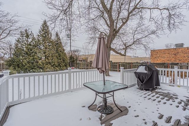 snow covered deck featuring area for grilling and a fenced backyard