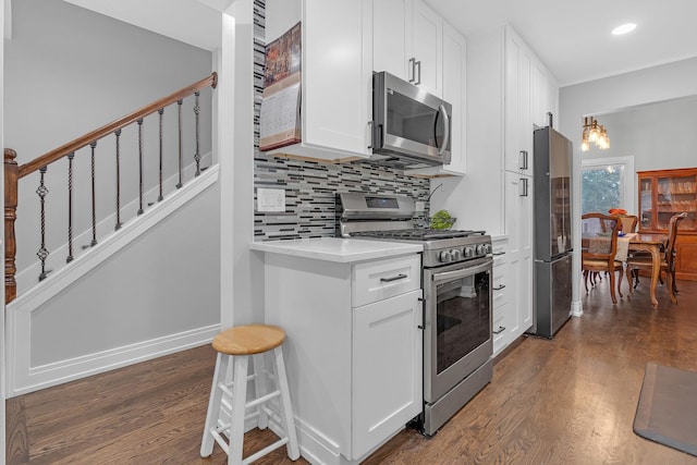 kitchen with stainless steel appliances, white cabinets, light countertops, and dark wood-style floors