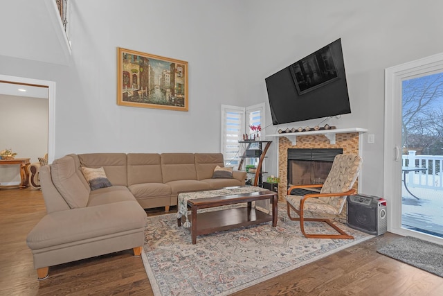 living area featuring a high ceiling, wood finished floors, and a tile fireplace