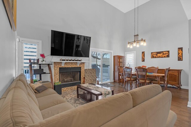 living area with high vaulted ceiling, baseboards, wood finished floors, and a tile fireplace