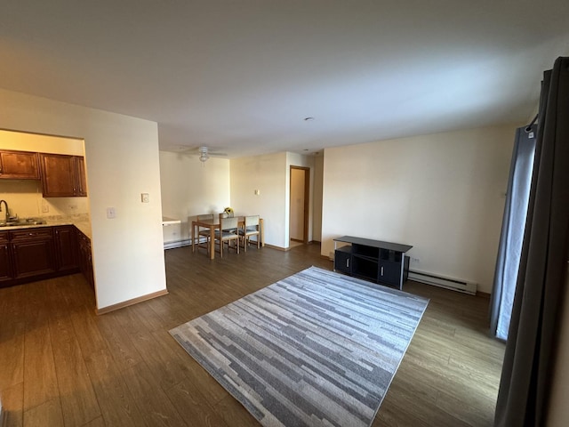 living room featuring a baseboard heating unit, dark wood-style flooring, baseboard heating, and baseboards