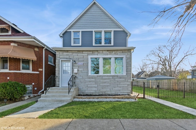 view of front of house featuring a front yard, stone siding, and fence