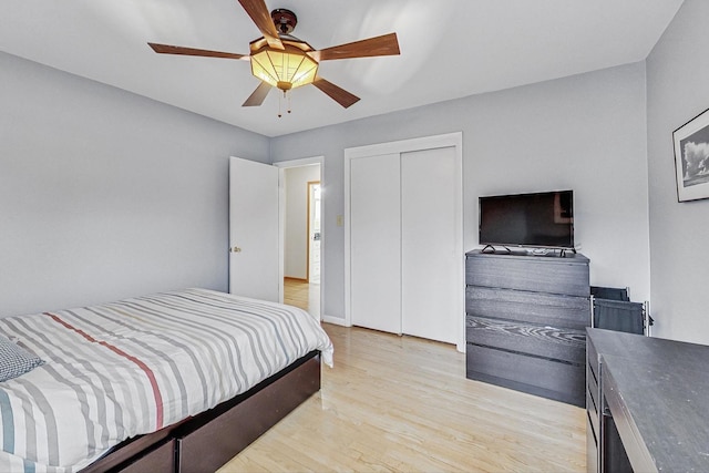 bedroom with light wood-style flooring, ceiling fan, and a closet