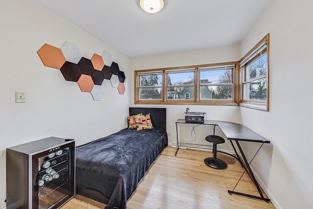 bedroom with wine cooler, wood finished floors, and baseboards