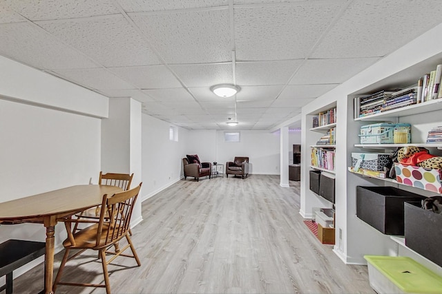 dining room with a drop ceiling, baseboards, and wood finished floors