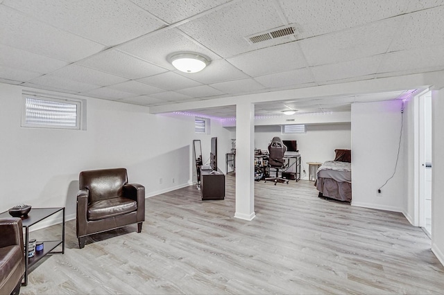 living area featuring a paneled ceiling, wood finished floors, visible vents, and baseboards