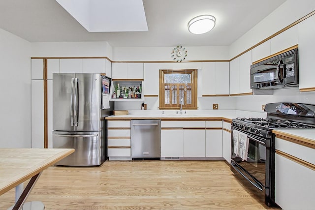 kitchen featuring black appliances, a sink, and white cabinetry