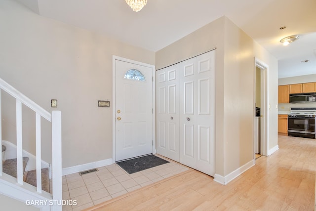 entrance foyer featuring stairway, baseboards, visible vents, and light wood finished floors