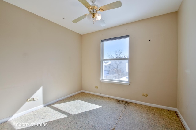 spare room with ceiling fan, visible vents, and baseboards